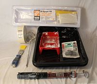 All painting and drywall preparation items laid out: wallpaper kit, trays, liners, mixer, spinner, putty knife, tape and patch kit