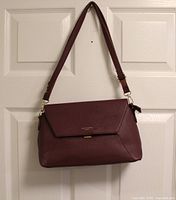 Front view of burgundy David Jones shoulder purse hanging on door