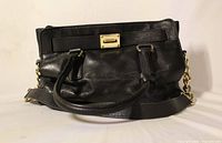 Front view of black leather Michael Kors handbag showing handles, chain strap and logo plaque