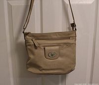 Front view of Rosetti beige crossbody purse hanging