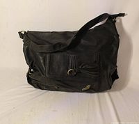 Full view of black Roxy shoulder purse showing exterior, front pocket, strap and hardware