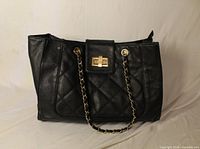 Front view of black quilted Aldo purse with chain straps and gold turn-lock
