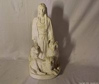 Front view of white cast sculpture showing Indigenous woman and wolves