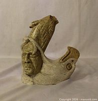 Full view of soapstone sculpture showing human face, fish head and seal figure