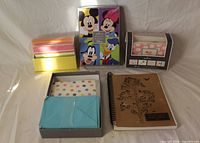 Entire lot showing five stationery items: multicolour card stack, polka-dot note card set, pink pattern note card set, Disney notepad/card set, kraft spiral notebook