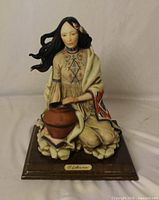 Full view of sculpture front showing figure, pot, base