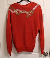 Back view of red sweater showing full sequin ribbon design and knit texture