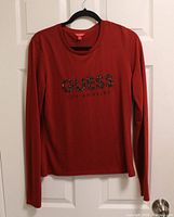 Front view of red Guess long-sleeve tee showing logo and overall condition