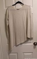 Front view of beige long sleeve Lululemon tee on hanger showing asymmetrical hem