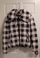 Front view of Juicy Couture Black Label black and white plaid puffer coat on hanger