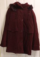 Front view of Nuage burgundy hooded winter coat hanging on door