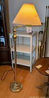 Full view of brass-tone floor lamp with shade and swing arm