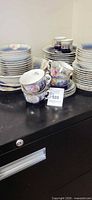 Stacked dinner and salad plates, teacups, saucers showing pattern and quantity