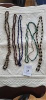 Five bead necklaces laid out showing full lengths and colours
