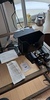 Binoculars, case, manuals laid out on glass table