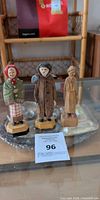 Three ANRI carved wood figurines on glass shelf