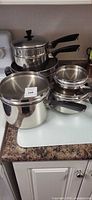 Full grouping of stacked stainless cookware on countertop