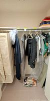 Closet rod with six coats, garment bags, scarves bin on floor