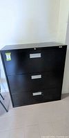 Front view of black three-drawer lateral filing cabinet