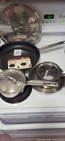 Group of pans and lids on stovetop: Paderno non-stick fry pan, Meyer saucepan with lid, stainless skillet with lid