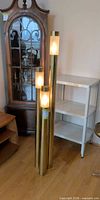 Full view triple tube brass-tone floor lamp lit