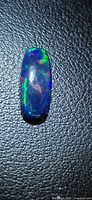 Front view of the elongated black opal showing multicolour play-of-colour
