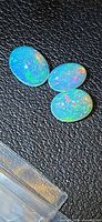 Three oval Ethiopian opals on dark background showing pinfire colours
