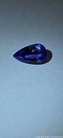 Pear-cut deep blue tanzanite profile view on neutral background