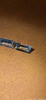 Two light blue baguette-cut gemstones on brown surface