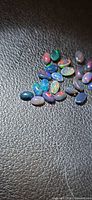 Group of small oval black opals on textured surface