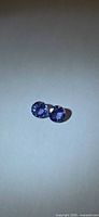 Pair of round violet-blue tanzanites on neutral background