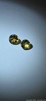 Pair of round golden yellow gemstones under spotlight