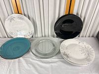 Group shot showing all seven plates: four snowflake, one black, one turquoise swirl, one clear glass