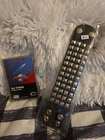 Front view of cassette in case beside packaged studded leather bracelet