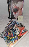 Stack and fan spread of assorted bagged comic books showing cover art, approximately 25 issues