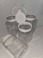 Five clear plastic jars with lids open showing flip-up caps