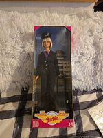 Front view of boxed Barbie pilot doll showing figure and accessories