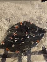 Front view of new black RIPNDIP butterfly bucket hat in plastic