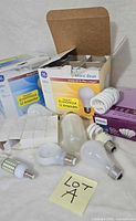 Group shot of boxed and loose bulbs including GE 12-pack, Philips 4-pack, LED bulb and others