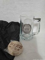 Glass mug with pewter MOM emblem, wood Beer Me coaster and packing tissue shown