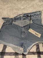Front view of high-rise denim shorts with tags attached