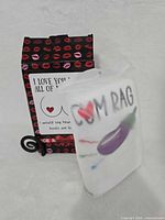 Folded white towel showing graphic and text beside original gift box