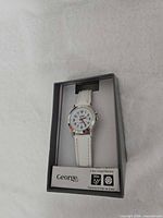 Front view of boxed George wristwatch showing dial, band, branding, warranty and water resistance icons