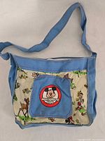 Front view of blue trim shoulder bag with Disney character print and Mickey Mouse Club logo pocket