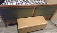 Footboard of wood sleigh bed with beige storage bench in front