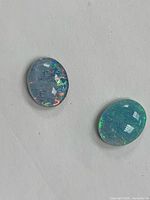 Two oval opal doublets loose on surface
