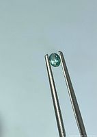 Gemstone held in tweezers side view