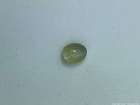 Top view of oval chrysoberyl cabochon on white background