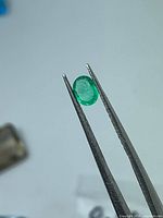 Emerald held in tweezers showing size and transparency