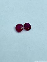 Two small round faceted red rubies on white background